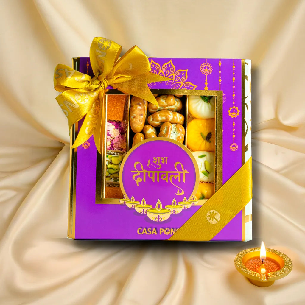 Gift box of assorted sweets with a Diwali theme on a beige fabric background