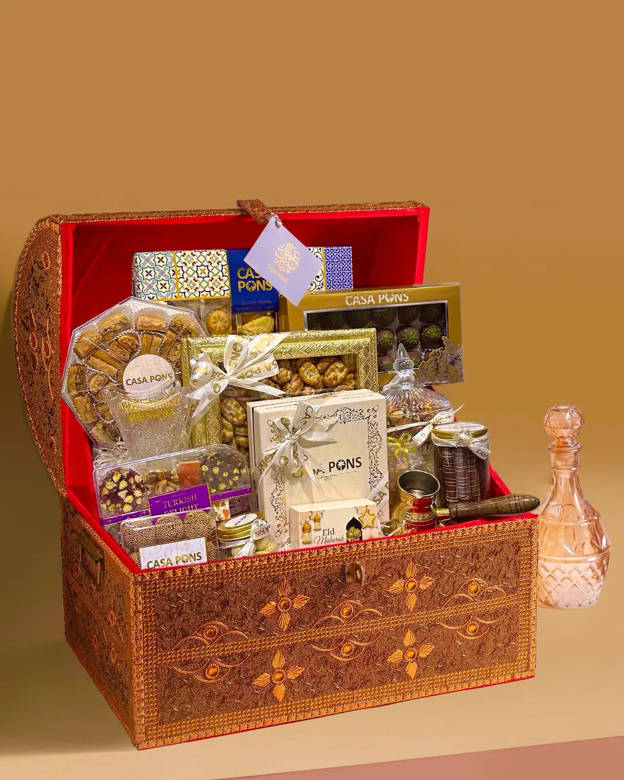 Medium Tresor gold treasure-style gift chest filled with Arabic sweets, maamoul, baklava, nuts, chocolates, Turkish delight, bukhoor, and coffee accessories.