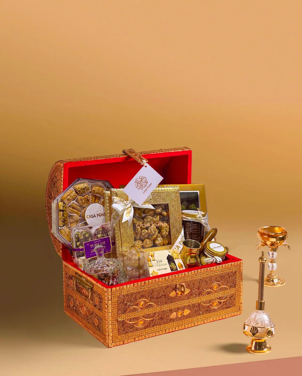 Small Tresor gold treasure-style gift chest with Arabic sweets, maamoul, baklava, nuts, chocolates, royal mix nuts, bukhoor burner, and Turkish coffee kanaka.