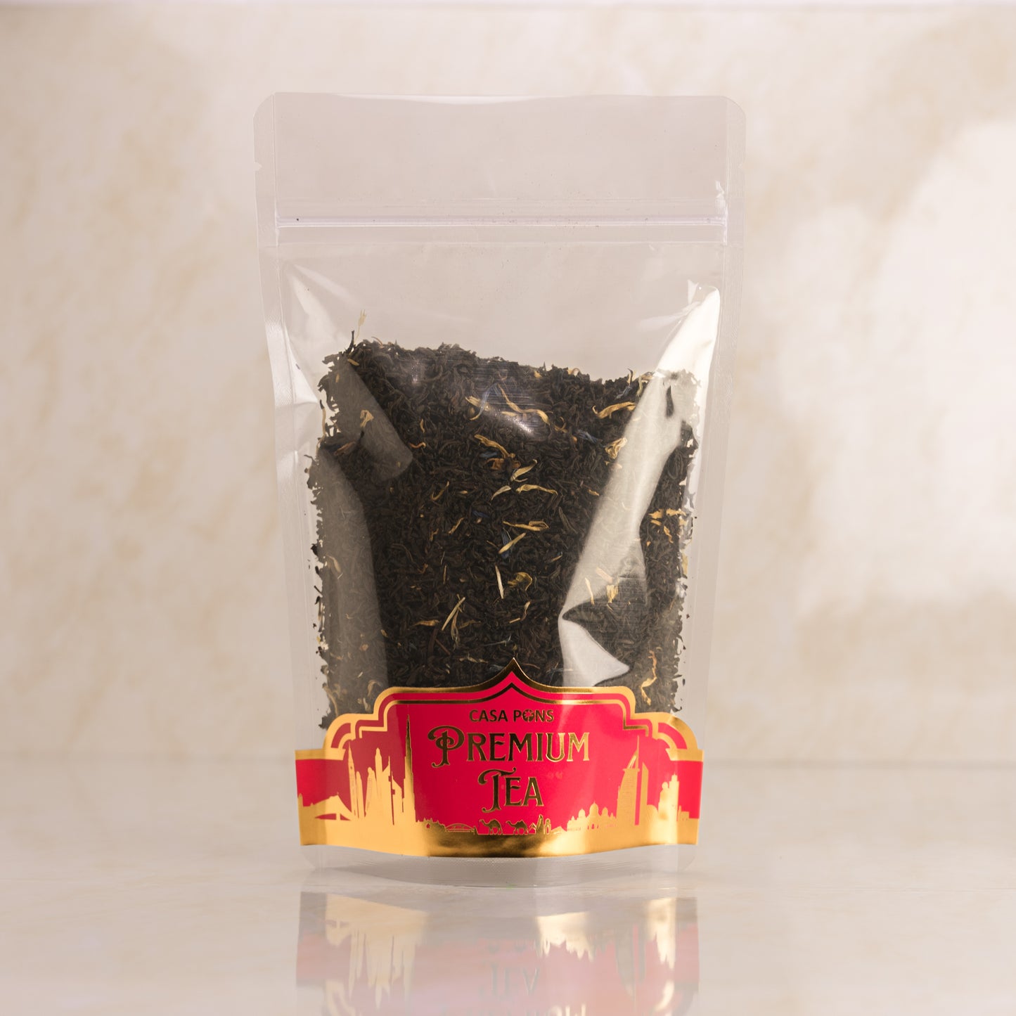 Clear plastic bag with black tea leaves and a red label on a beige background