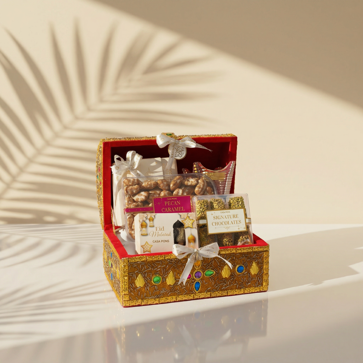 Decorative gift box with snacks and chocolate on a reflective surface with a neutral background