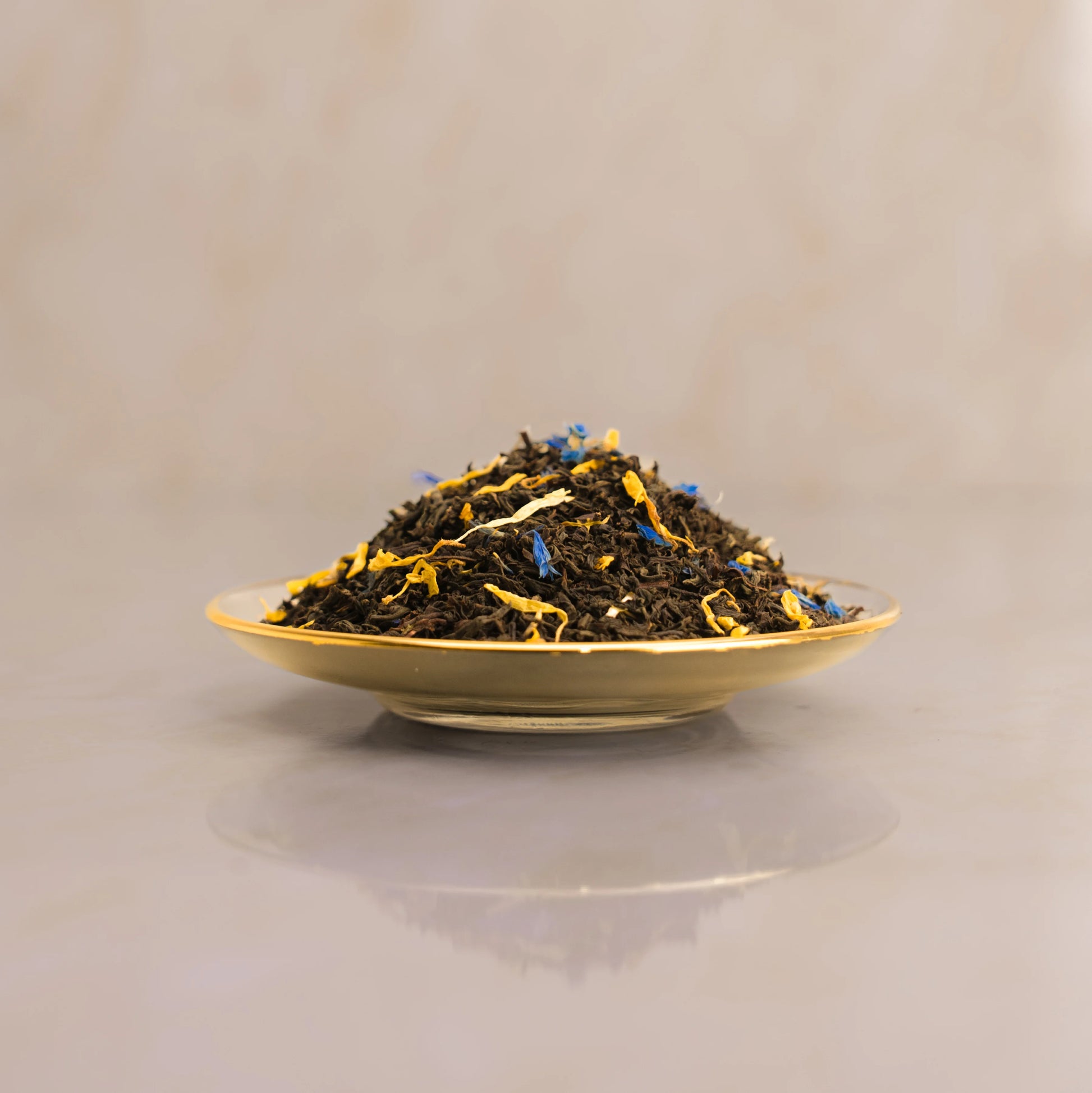 Tea leaves on a gold plate with a beige background