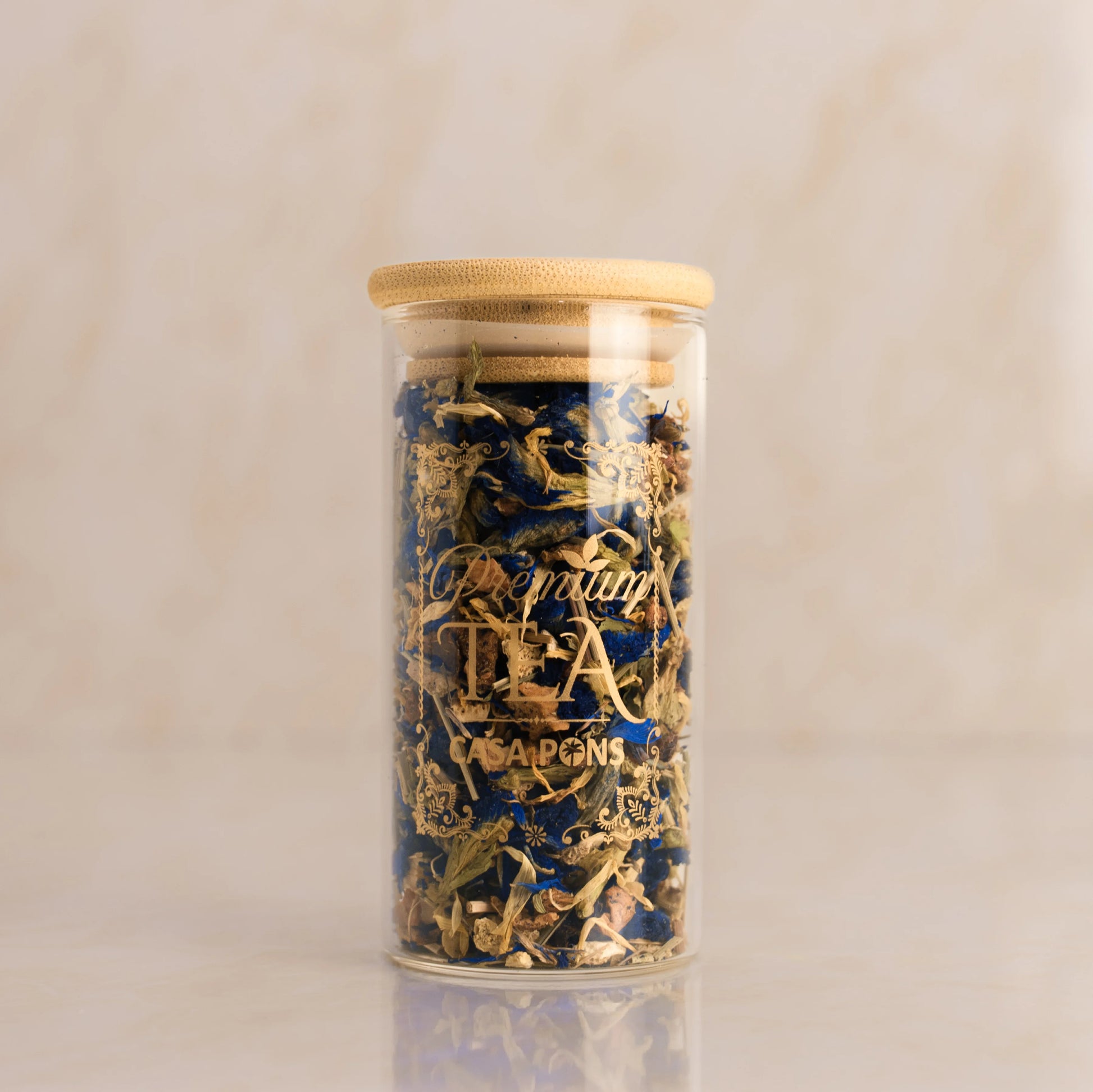 Glass jar with gold and blue contents on a beige background