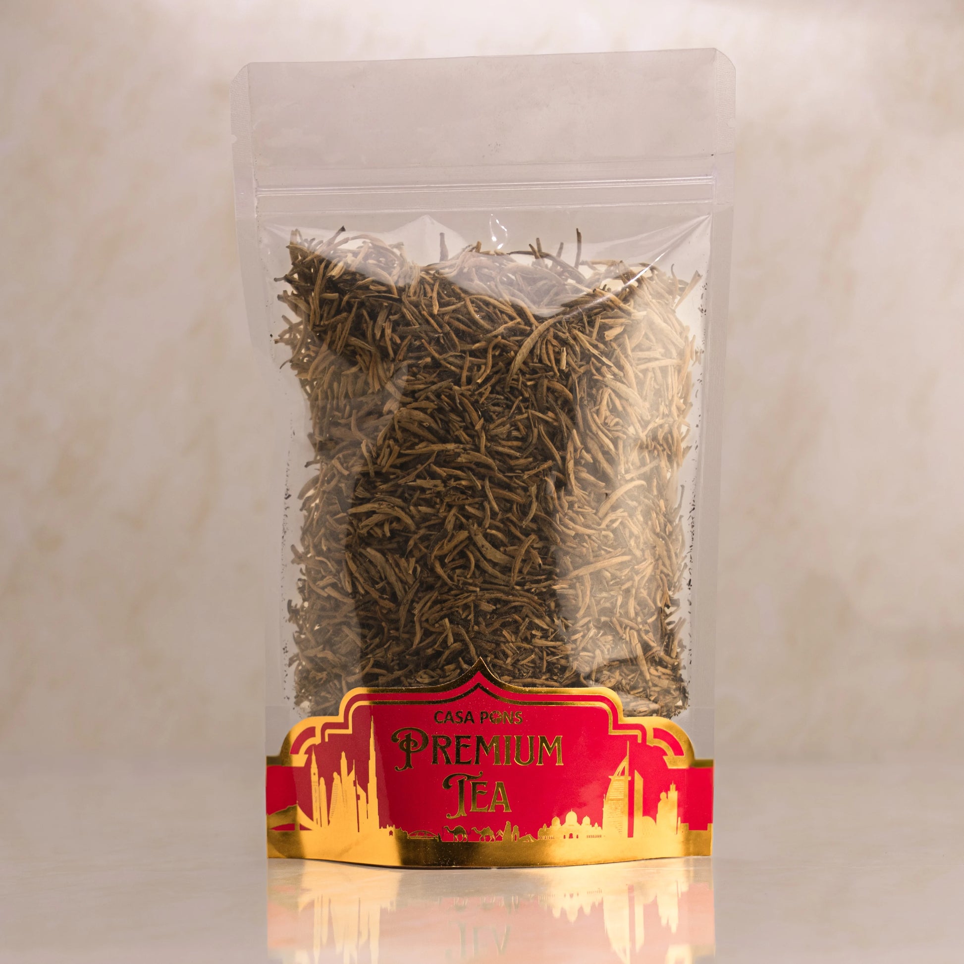 Clear plastic bag with dry tea leaves and a red label on a beige background