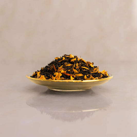 Dry black tea leaves on a beige plate with a plain background
