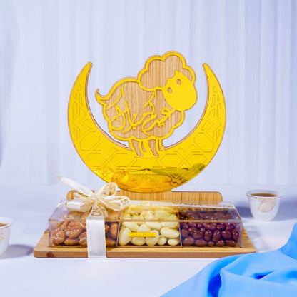 Decorative glass dish with sheep design on a crescent moon, placed on a wooden board with snacks.