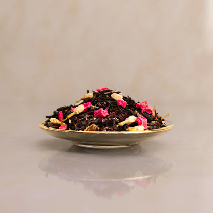 Tea leaves with pink flowers on a reflective surface with a neutral background