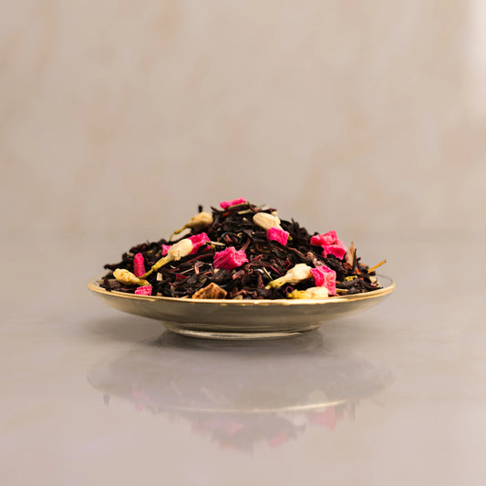 Tea leaves with pink flowers on a reflective surface with a neutral background