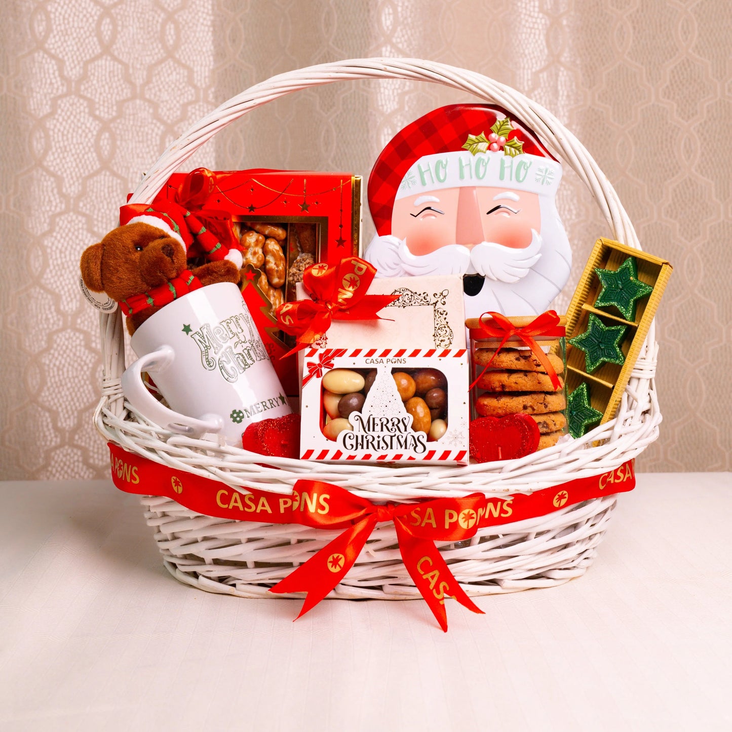 Christmas gift basket with Santa Claus figure, mug, and assorted treats on a neutral background