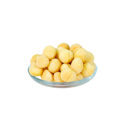 A clear glass bowl filled with roasted, salted macadamia nuts against a black background.