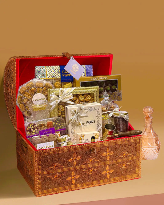 Medium Tresor gold treasure-style gift chest filled with Arabic sweets, maamoul, baklava, nuts, chocolates, Turkish delight, bukhoor, and coffee accessories.