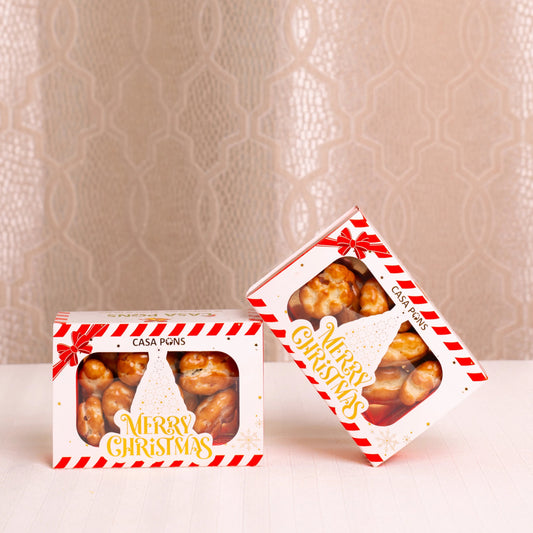 Two Christmas-themed boxes of Casa Pigna snacks on a textured beige background