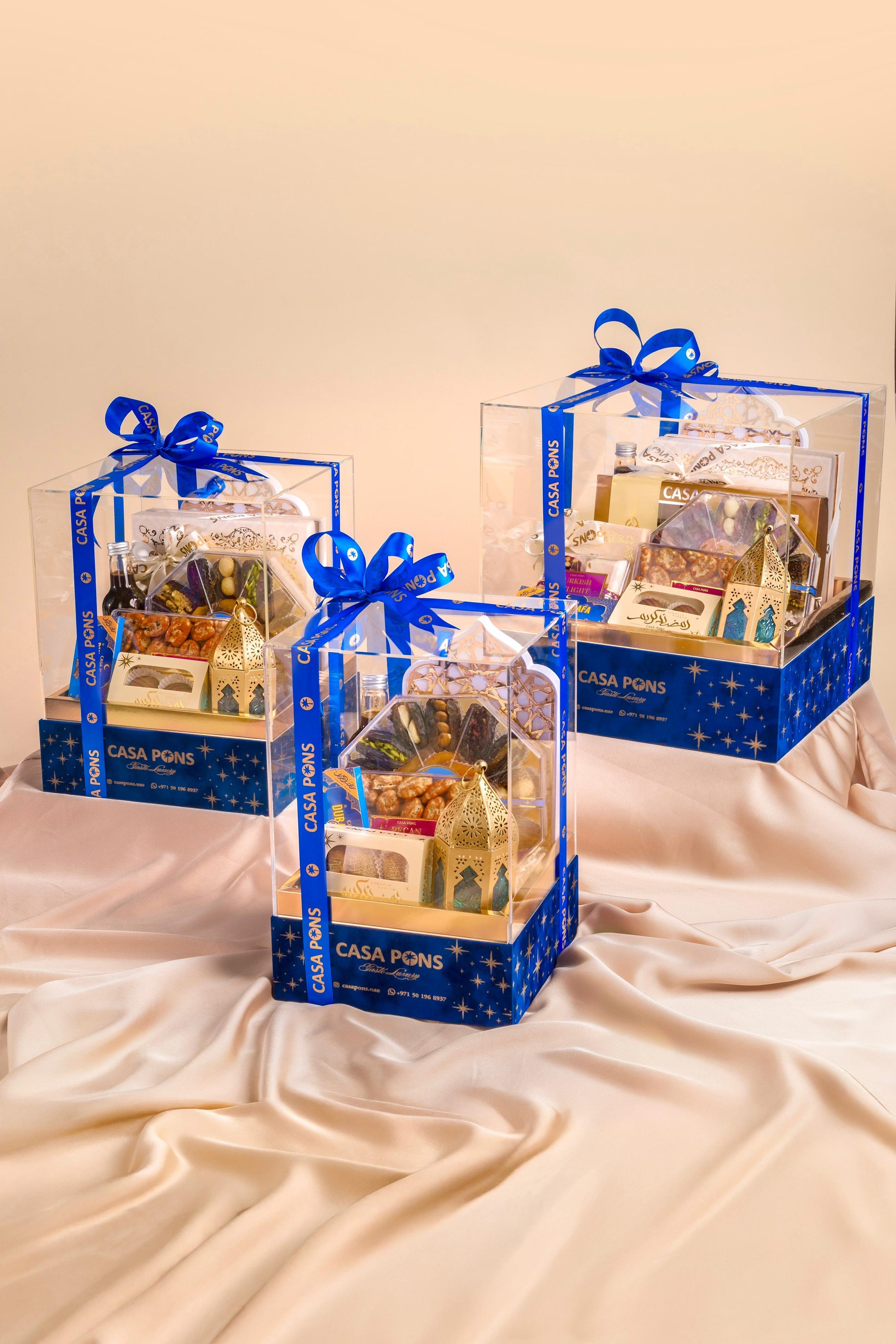 Three gift boxes with blue ribbons on a beige surface