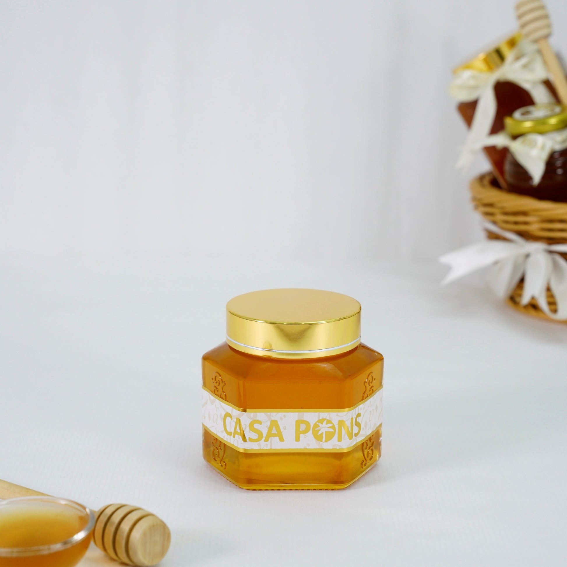 Honey jar with gold lid and 'Casa Pons' label on a white background