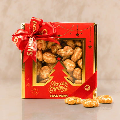 Gift box with roasted chestnuts and a red ribbon on a beige background