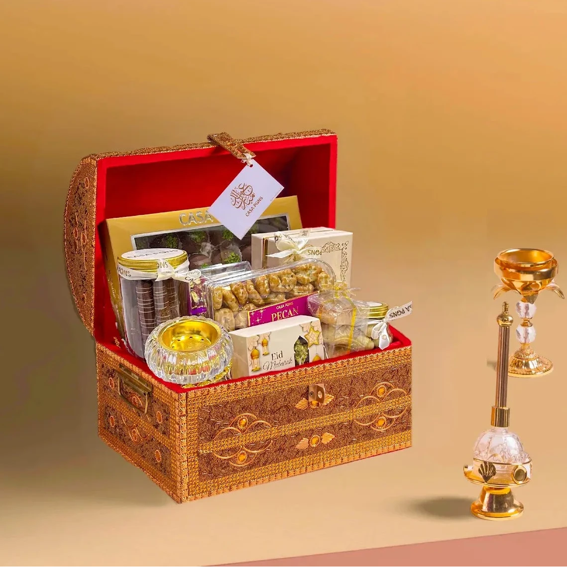 Decorative gift box with snacks and a small lamp on a beige background