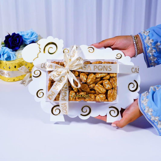 Hand holding a box of Casa Pons white sheep Eid tray with decorative elements on a light background