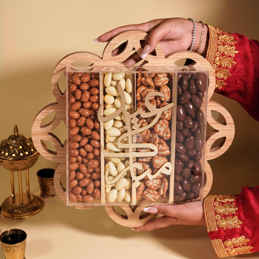 Hand holding a wooden box of assorted nuts with a decorative background
