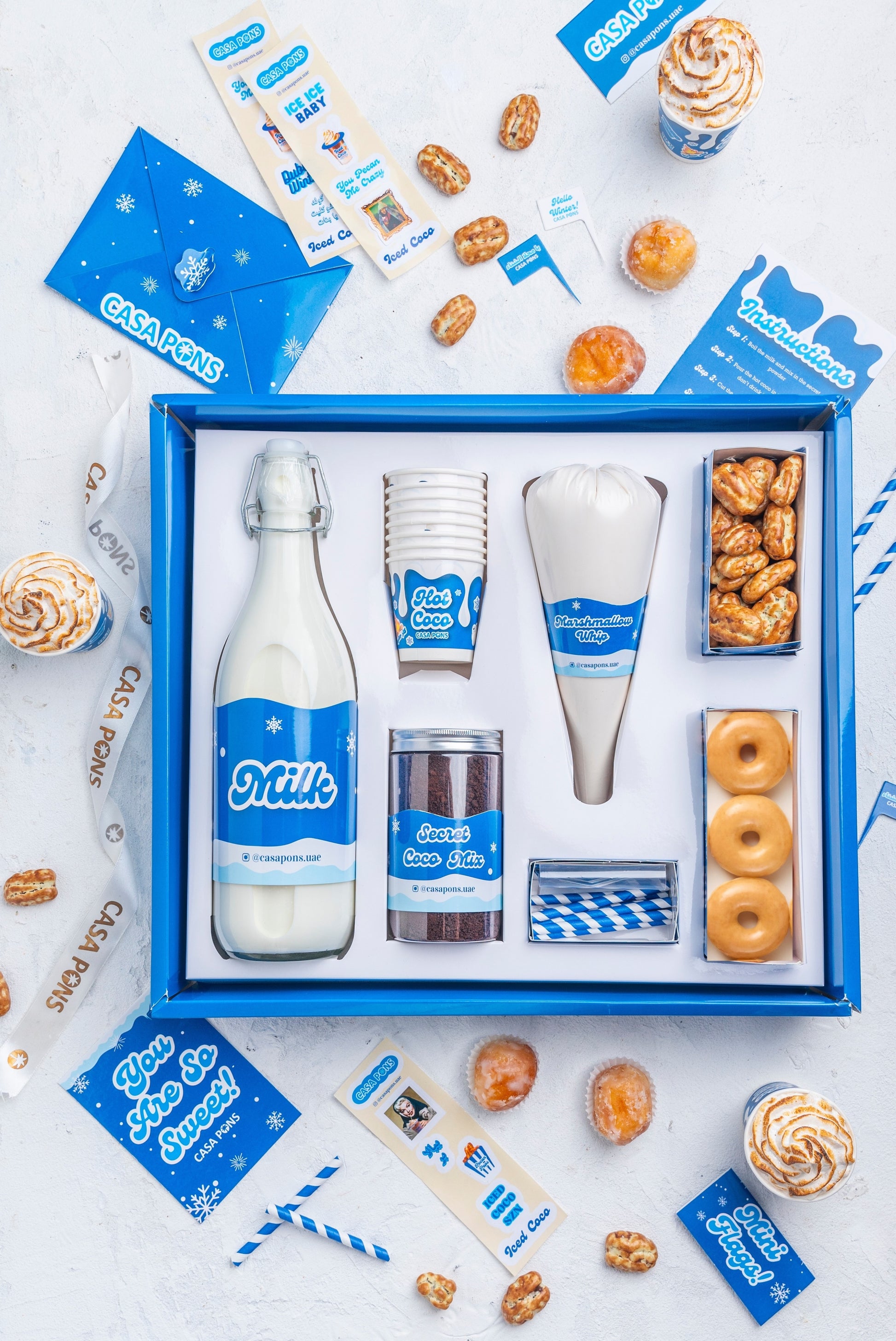 Gift set with milk-themed items including a bottle, cups, and snacks in a blue box.