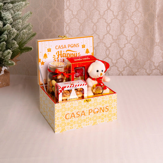 Gift box with 'Casa Pons' branding containing a teddy bear and various items on a neutral background.