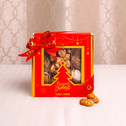 Red gift box with a Christmas tree design and 'Season's Greetings' text, containing chocolates on a light background.