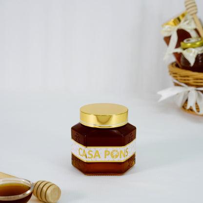 Jar of Casa Pons honey with a gold lid on a white background